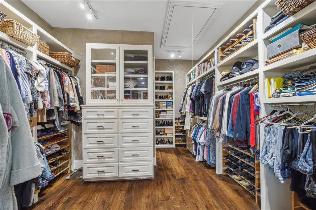 Large primary closet with lots of storage space including glass front cabinets, shoes display shelves and generous hanging options.