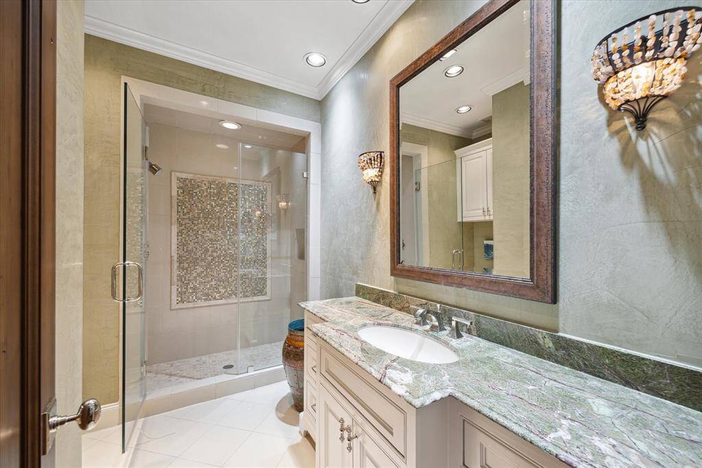 Curated stone vanities, frameless shower enclosure are in keeping in the custom home.
