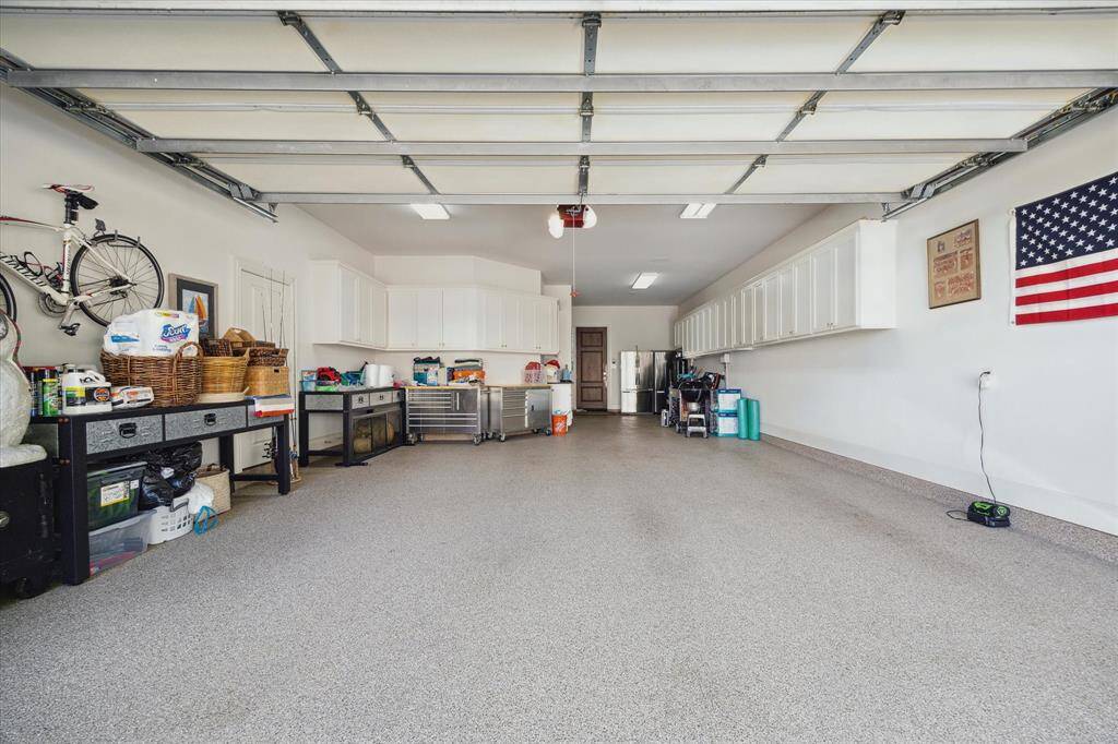 Large 3 car tandem garage with upper storage cabinets and plenty of room for bikes and workspaces shines with the epoxy floors!