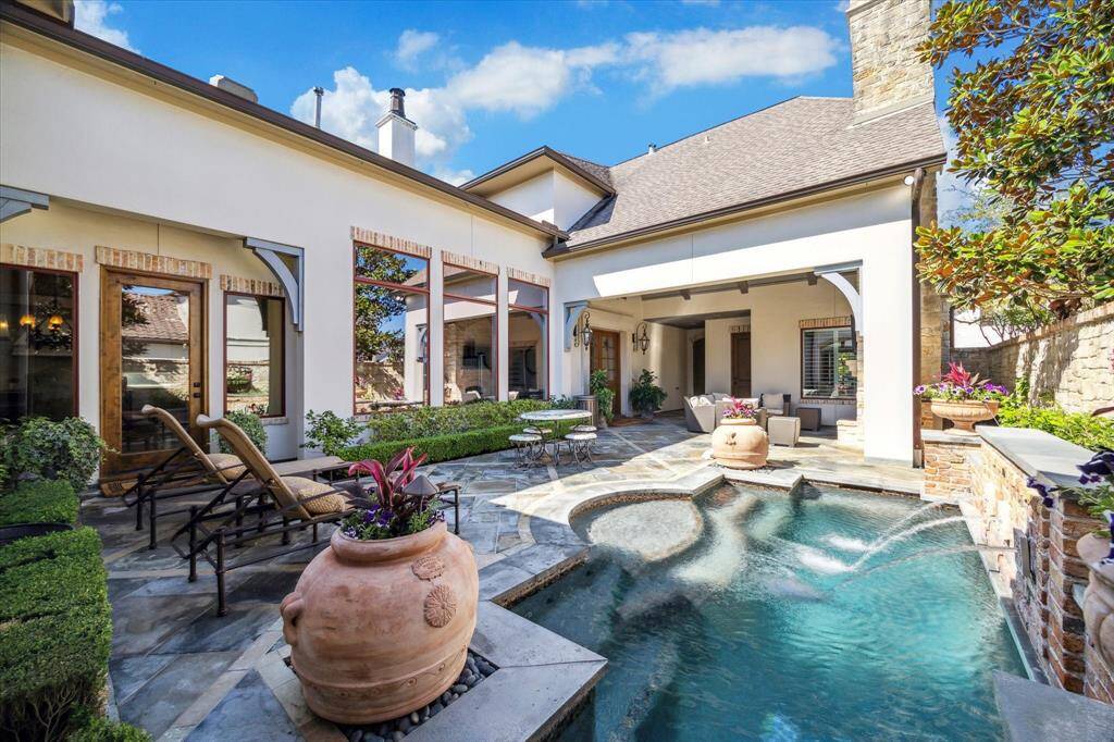 Serene with capacity for lively entertaining, this courtyard features Pennsylvania Blue Stone decking with accents of reclaimed brick. This area has a lovely cocktail pool with a water feature and a summer kitchen with vaulted ceiling living area.