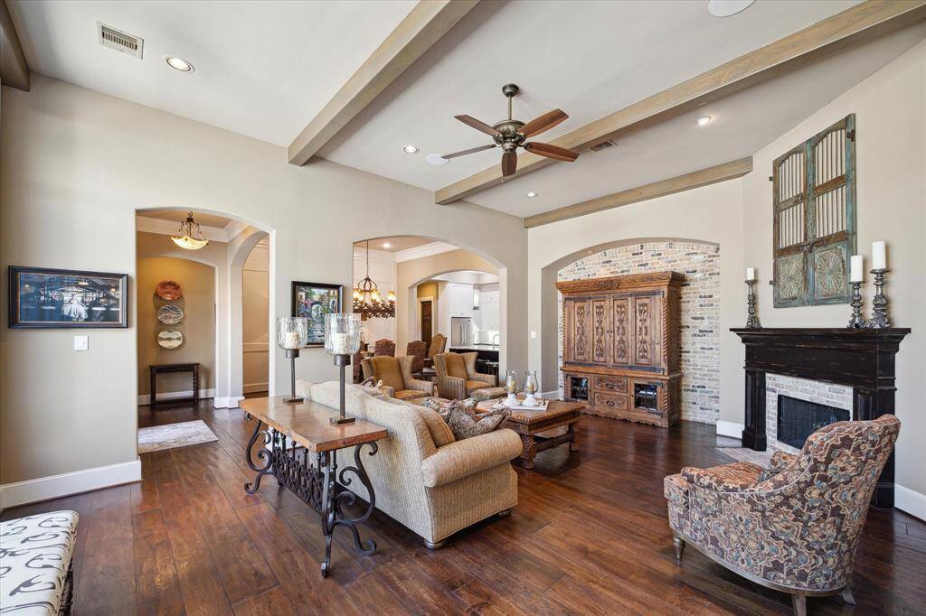 The open family room with fireplace and accent brick wall offer a great space to relax and unwind. A wall of windows and French doors provide views of the pool and outdoor living space for seamless entertaining.