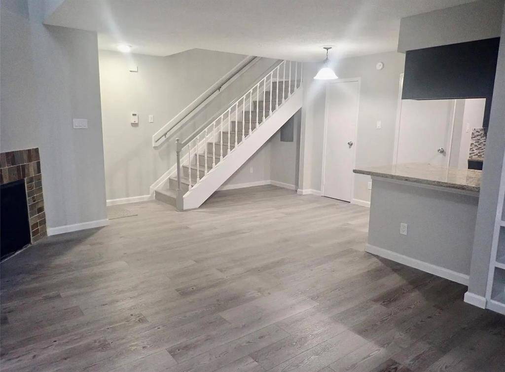 Modern living room featuring sleek hardwood floors, a cozy fireplace, and an inviting open layout connected to the kitchen. Perfect for relaxing and entertaining.