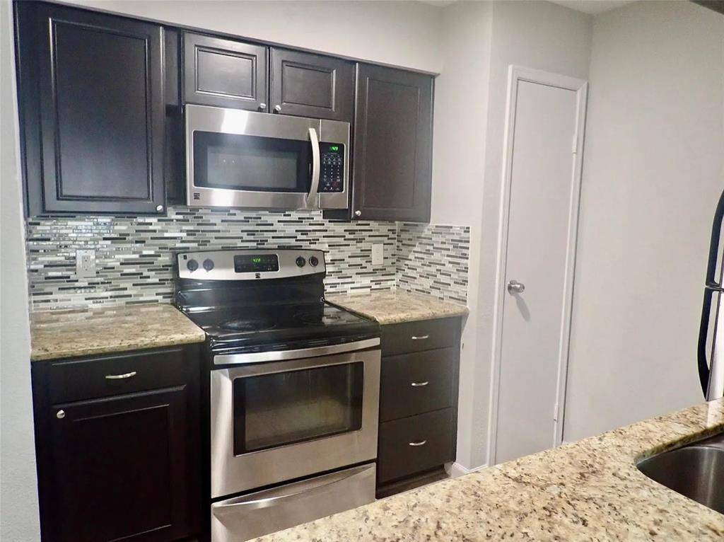 Modern kitchen featuring sleek stainless steel appliances, elegant granite countertops, and stylish mosaic tile backsplash. Perfect for culinary enthusiasts.