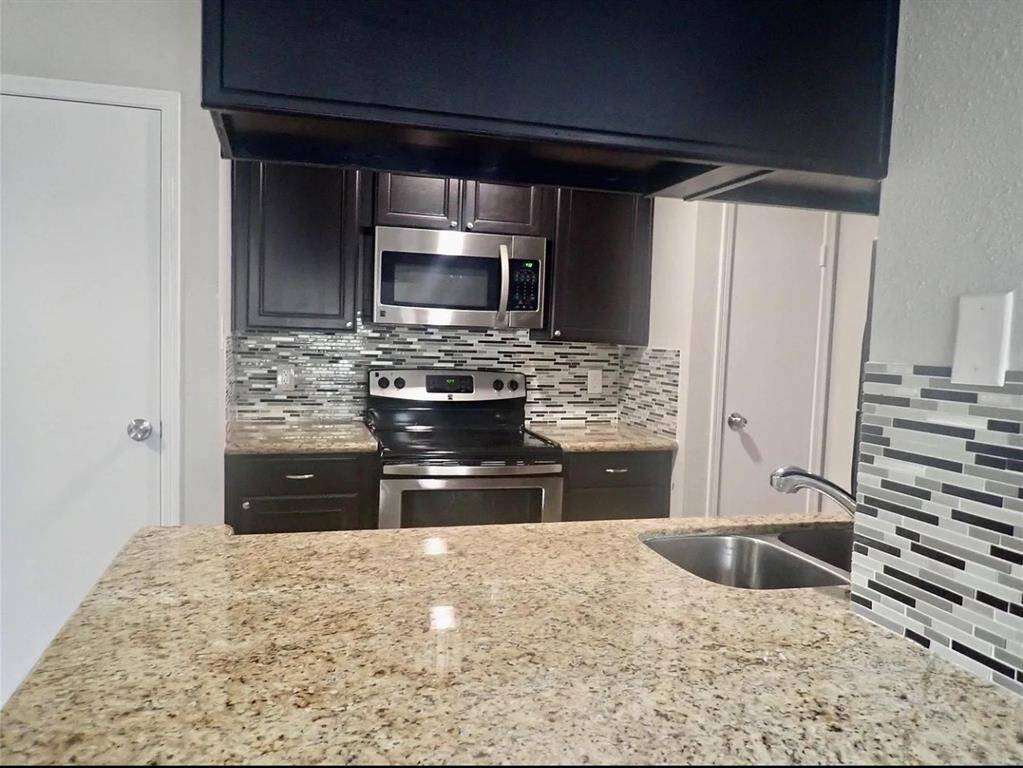 Modern kitchen with sleek stainless steel appliances, elegant granite countertops, and stylish tile backsplash. Perfect for both cooking and entertaining.