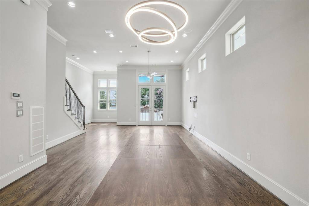 Another view of dining/living room, hardwood floors and lots of light from windows. Beautiful chandelier that is staying with the home.