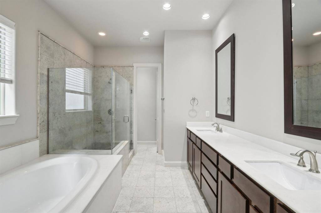 Master bathroom, with separate sinks, separate tub and big walk in shower with granite tile on the wall and the floors.