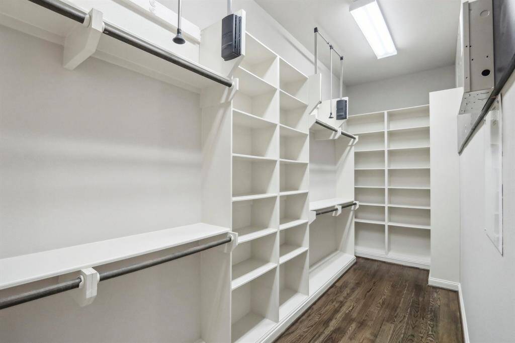 Long walk in closet with lots of built ins and rods that pull up and down to make it easier to store heavy coats etc.