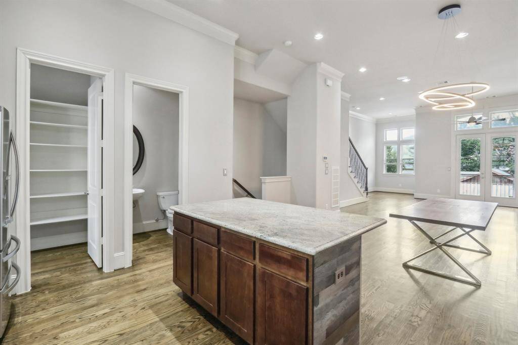 View of part of the pantry with half bath and dining/living combo. Plus a balcony leading out of second floor from living area. Hardwood floors throughout the house.