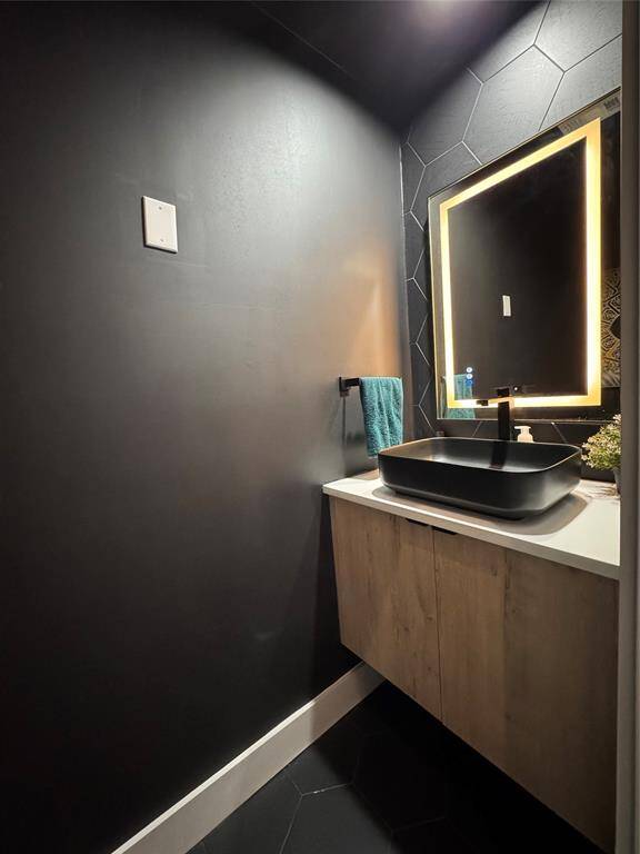 Powder room 1st floor featuring snake skin tile, front and back lit mirror