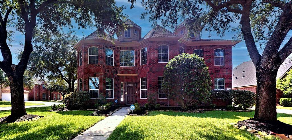 Charming brick home with elegant windows and lush landscaping, creating inviting curb appeal.