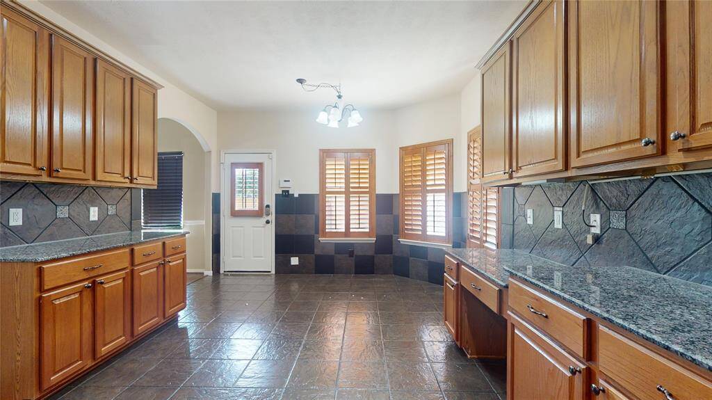 Explore culinary delights in this stunning kitchen, featuring sleek granite countertops, ample cabinetry, and elegant tile flooring. Perfect for both everyday cooking and entertaining.