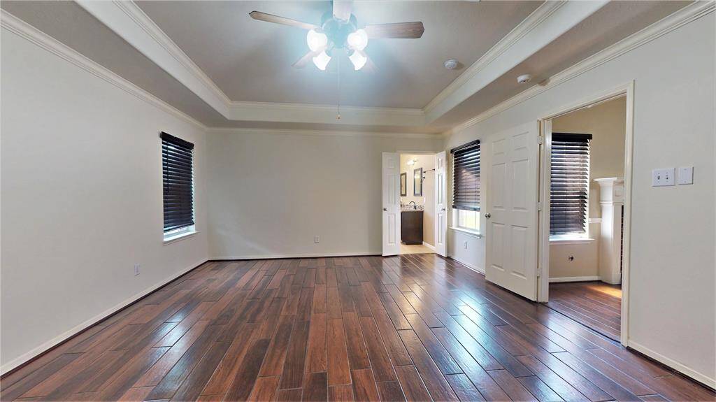 Luxurious primary bedroom featuring an elegant tray ceiling and refined crown molding.