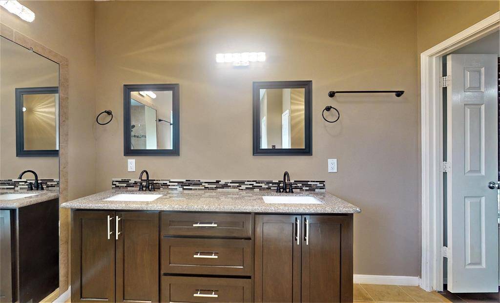 Elegant primary bathroom featuring a sleek double vanity, modern fixtures, and ample storage.