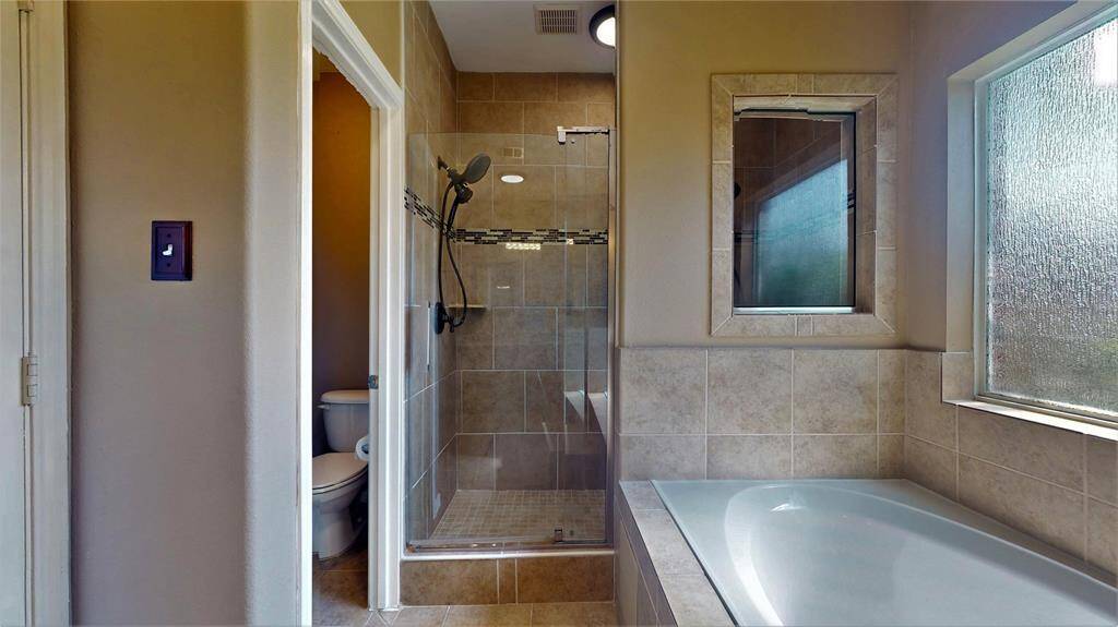 Updated in 2021, the primary bathroom features double sinks, a luxurious jacuzzi tub with steps, a dual shower-head system, and a large wall mirror.