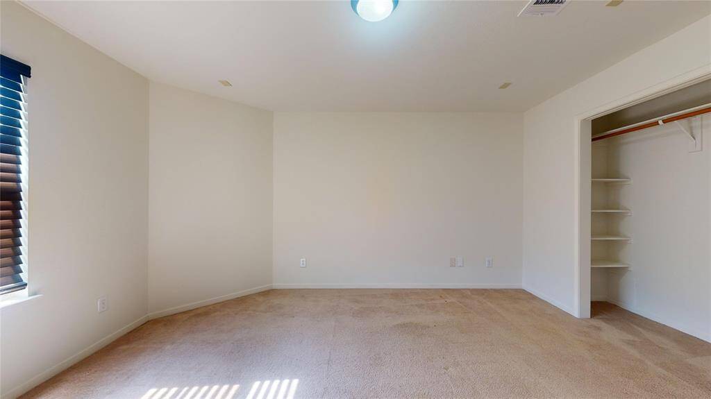 Bright guest bedroom featuring three large windows for ample natural light.