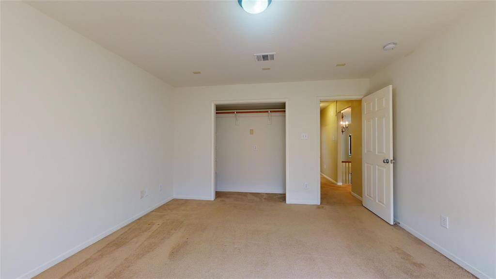 Spacious guest bedroom with ample closet space and soft carpeting, perfect for comfort and relaxation.