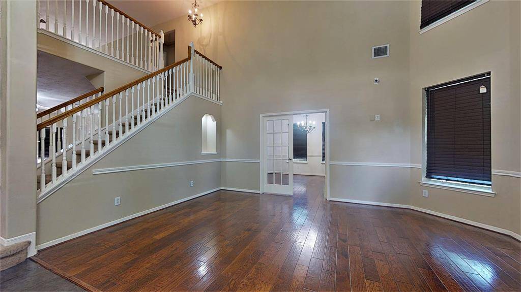 Discover a spacious living room featuring elegant hardwood floors, abundant natural light, and a stunning high ceiling, perfect for entertaining or relaxing.