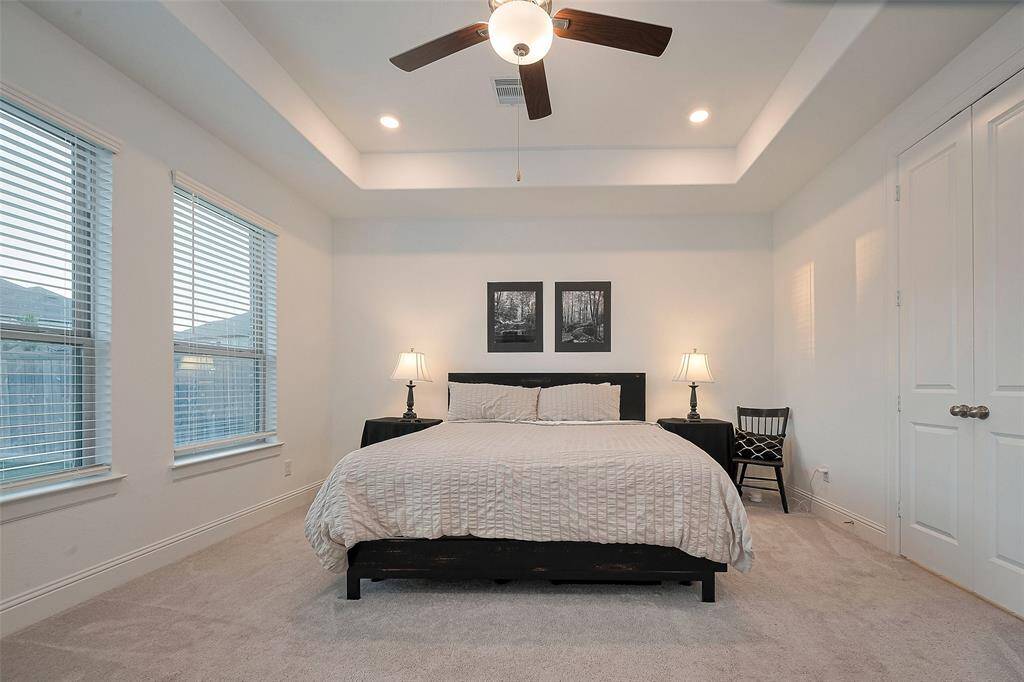 Experience ultimate relaxation in this spacious primary suite, featuring elegant tray ceilings, abundant natural light, and a serene ambiance.