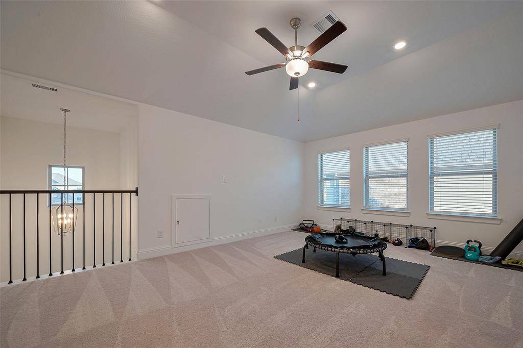 This large game room offers a bright, inviting space with large windows and plush carpeting, perfect for entertainment and relaxation.