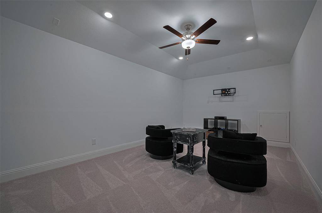 The cozy media room is perfect for movie nights, featuring ample space for comfortable seating and a ceiling fan for optimal comfort.