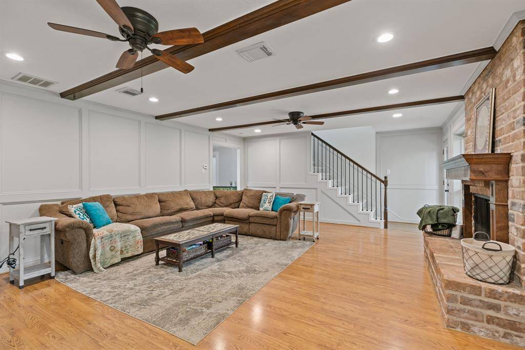 The den is accented by wood look beams, ceiling fans, canned lighting and brick fireplace.