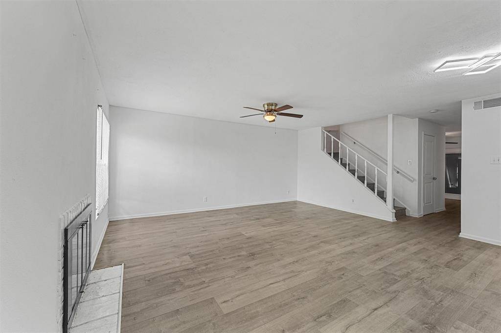 spacious living room with a fireplace. The room is bright with natural light and features an open staircase leading to the upper level.