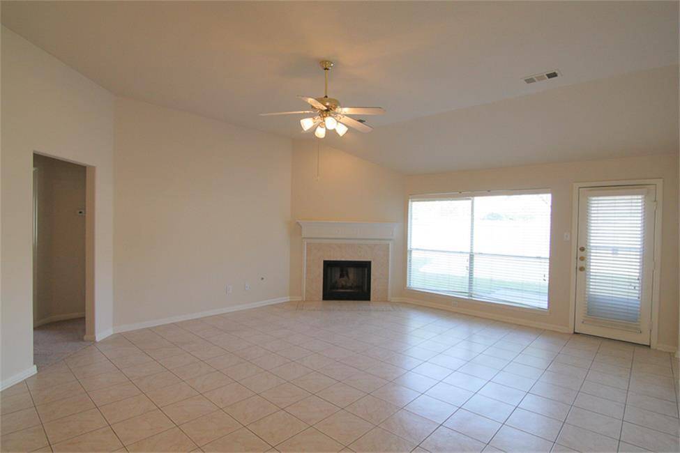 spacious family room with vaulted ceiling, ceramic tile, gas fireplace with mantel and tile surround, and large windows with view of backyard