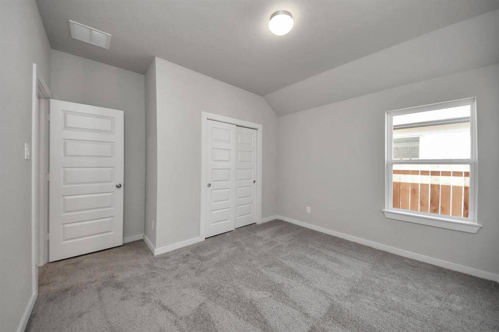 Secondary bedroom features plush carpeting, large windows that let in plenty of natural light, bright paint, and spacious closets. Sample photo of completed home with similar floor plan. Actual colors and selections may vary.
