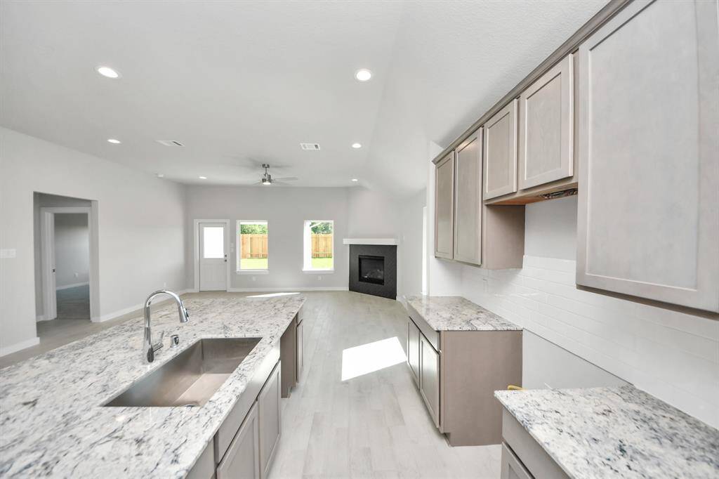 This generously spacious kitchen is a dream realized! With a massive granite island, high ceilings, soft close cabinets, granite countertops, stainless steel appliances, a sleek tile backsplash, recessed lighting, and an extended counter area, it offers both style and practicality. All this opens up to the expansive family room, creating a perfect hub for gatherings. Sample photo of completed home with similar floor plan. Actual colors and selections may vary.