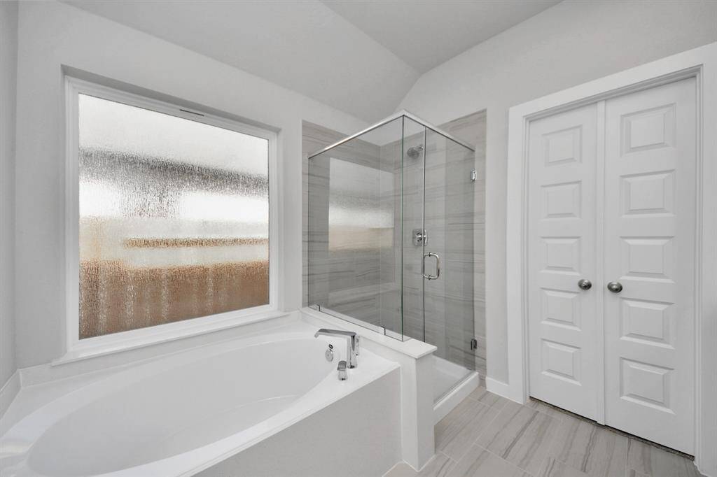 This additional view of the primary bath features a walk-in shower with the tile surround and separate garden tub perfect for soaking after a long day. Sample photo of completed home with similar floor plan. Actual colors and selections may vary.