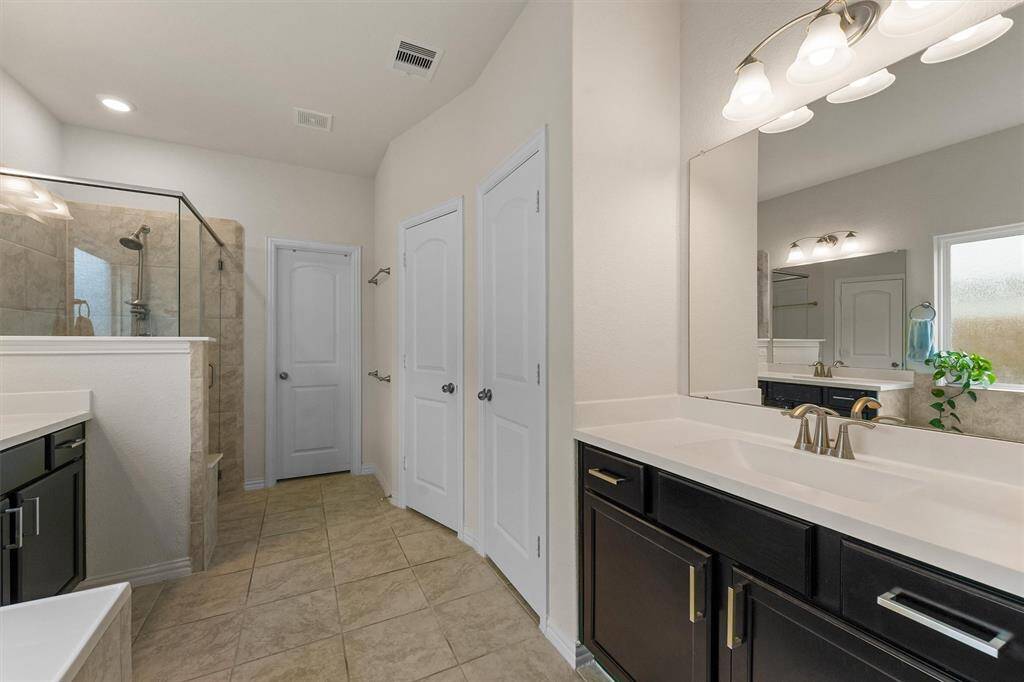 Primary bathroom with double vanities with cultured marble countertops