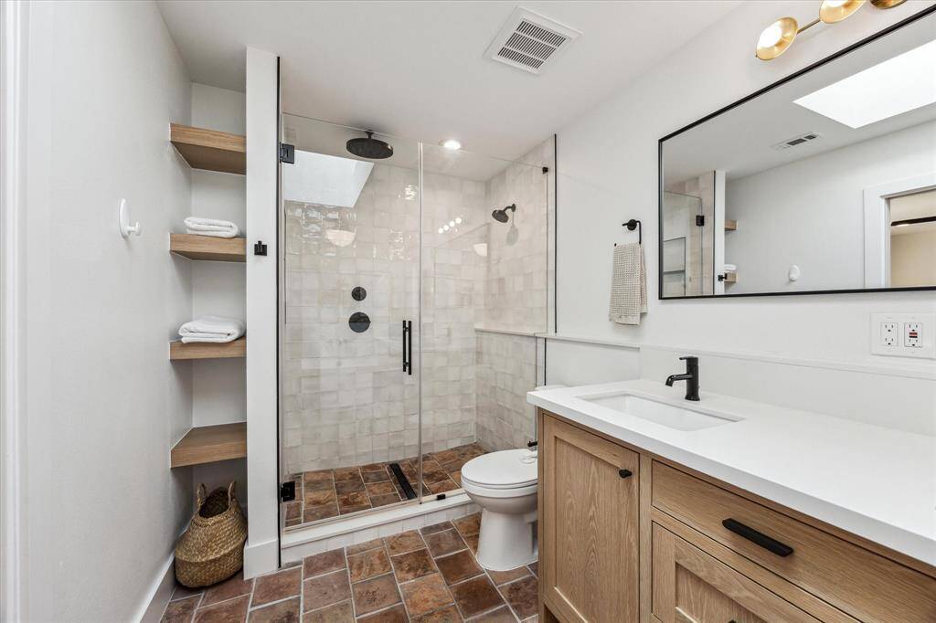 The glass enclosed shower features dual shower heads (one is a rainfall showerhead). The bathrooms hardware and fixtures are matte black and from Rejuvenation.