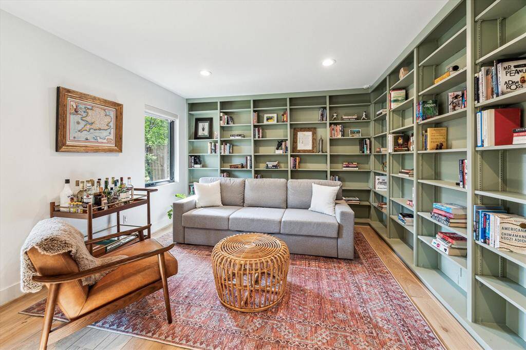 Two walls of floor to ceiling sage green bookshelves line the study.