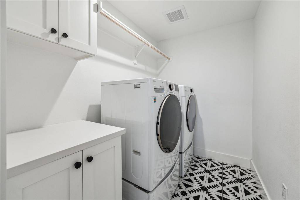 Spacious laundry room with stylish tile, drying bar and storage.