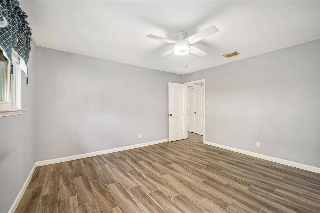 Off the family room is a hall to the bedroom area. Primary bedroom is the first room to the right as enter the hallway. The roomy bedroom with the same wood tile floors, updated ceiling fan, enhanced base boards with an en-suite bath.