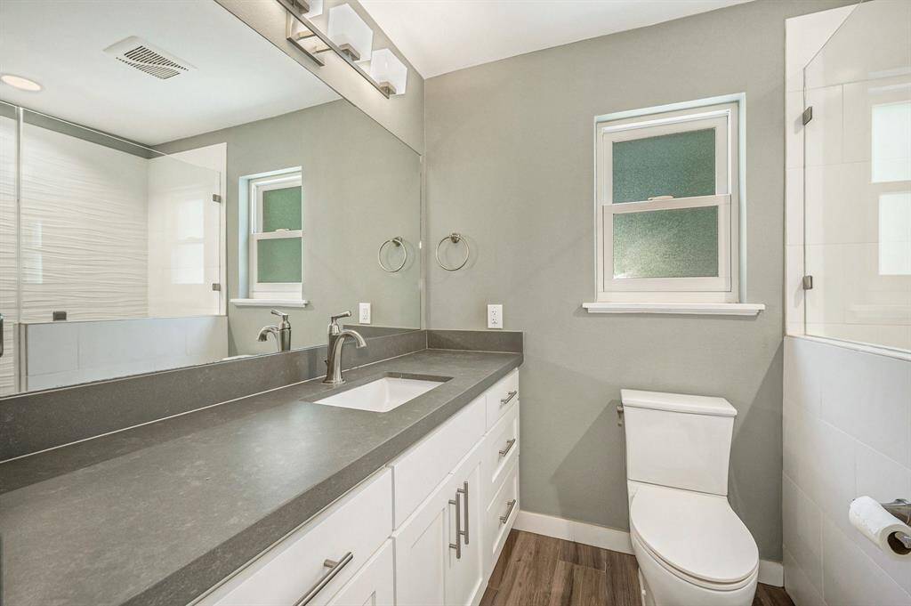 Primary bathroom has been renovated to give a modern look with shaker cabinets, recent toilet, rain water window and modernized lighting.
