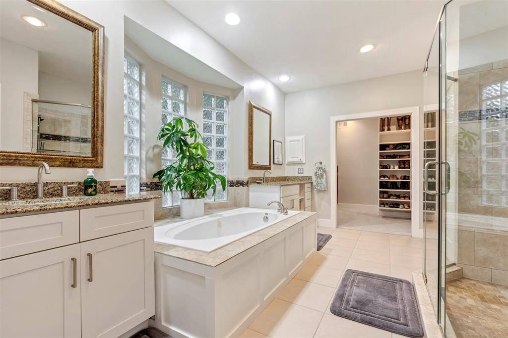 The en-suite bath feels like a private spa, with two sinks, granite countertops, a jetted soaking tub, and a separate shower. There’s also a vanity area and a walk-in closet that offers plenty of space to stay organized.