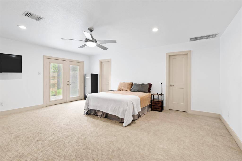 Enter your primary bedroom nestled on the first floor. Complete with soft neutral carpeting, recessed lighting, and a sleek ceiling fan for year-round comfort. French doors open to the backyard, filling the room with natural light and offering a private outdoor entrance. Dual interior doors lead to your en-suite bath and spacious walk-in closet, providing both convenience and comfort.