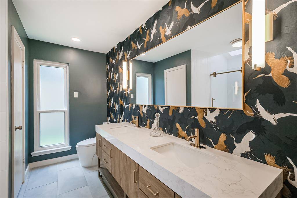The stunning primary bathroom has been renovated with tile floors, quartz counters, updated vanity, champagne bronze faucets, double sinks and a framed mirror. There is also a toilet with a bidet.