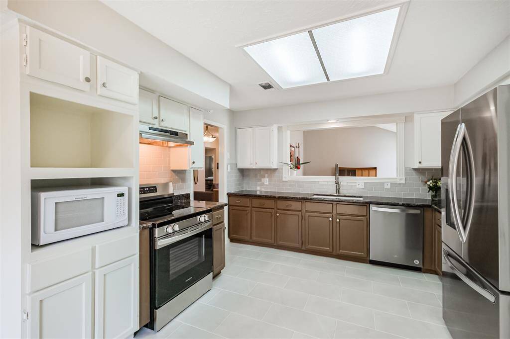 The spacious kitchen has granite counters with recent subway tile backsplash.