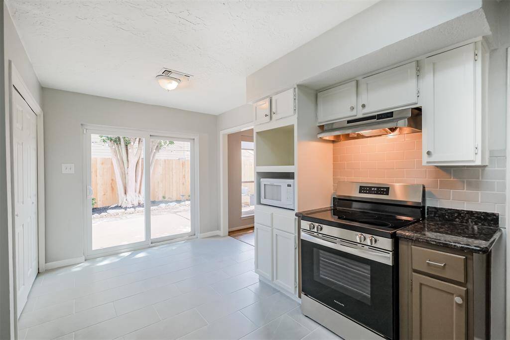 There is a stainless steel electric range with vent hood.