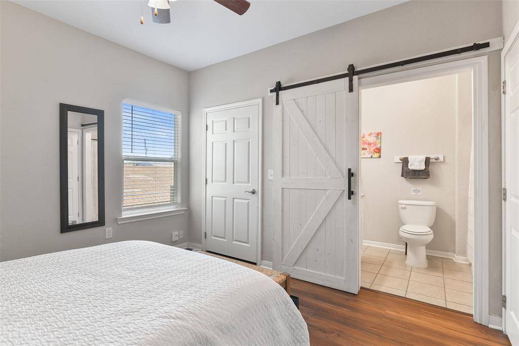 Looking the other direction in the master suite, a stylish sliding barn door leads to an ensuite bathroom. Alo note the large window for natural light & full-length wall mounted mirror.