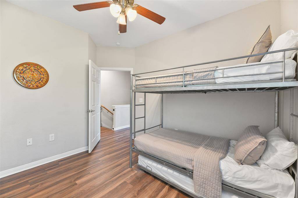 Another secondary bedroom is also equipped with a metal frame bunk bed, a lighted ceiling fan, a sunlit window and luxury vinyl plank floors.