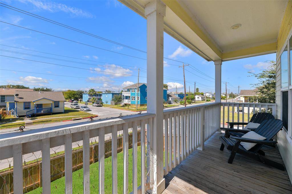 A spacious covered balcony offers a relaxing view of a quiet neighborhood street, perfect for enjoying morning coffee.