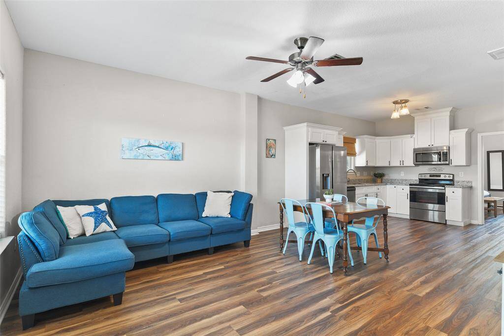 This open-concept living space features a cozy blue sectional and a seamless transition to the modern kitchen with stainless steel appliances, and luxury vinyl plank flooring throughout. Perfect for entertaining and family gatherings!