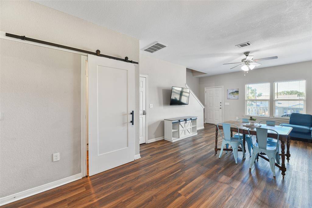 Looking back towards the entrance to the home, note the open layout with a cozy dining area, and ample natural light from large windows. A sleek barn door adds a stylish touch and conceals the first floor utiilty room.