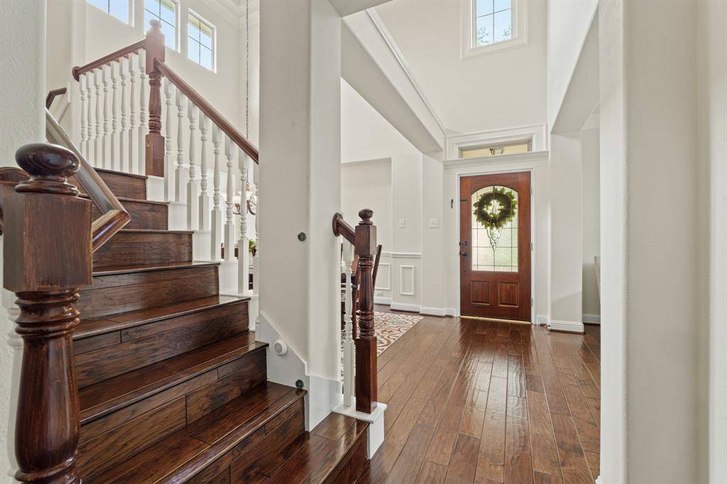 A dramatic two-sided staircase—accessible from both the kitchen and primary suite—features beautiful wood steps.