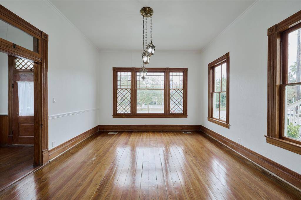 Bright and spacious room features an elegant archway and wooden staircase that add to the home's charm, while the neutral walls provide a versatile backdrop. Rooms are versatile and this space is perfect for a living or dining area.