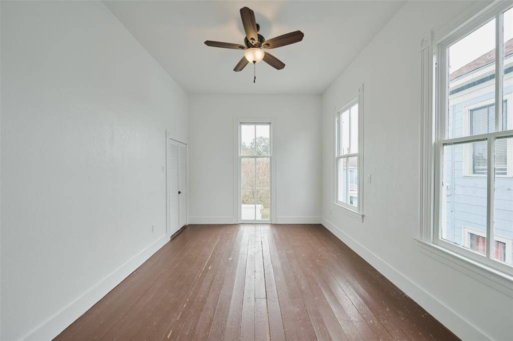 The primary bedroom boasts abundant natural light, historic wood floors, and a walk-in closet, with an elegant ensuite bathroom accessible through a charming pocket door.