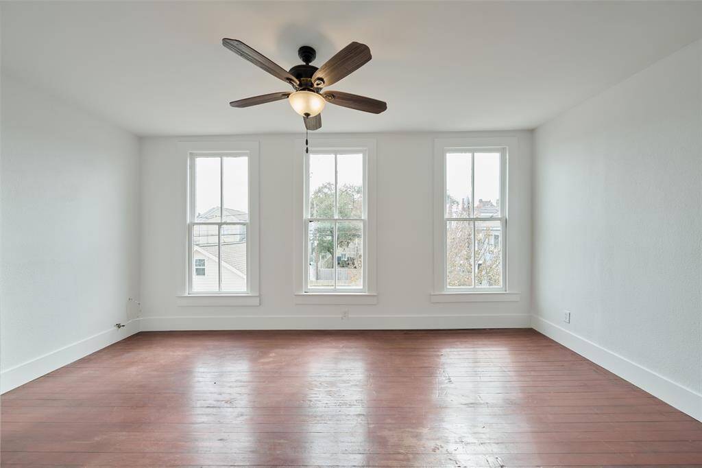 This charming two-story home features a white exterior with multiple windows, allowing ample natural light to flow in. The backyard includes a cozy wooden deck perfect for outdoor relaxation and entertaining. A wooden fence offers privacy, and neighboring homes add to the community feel.